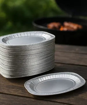 Rustieke houten tafel met daarop een serverschaal vol gegrild vlees en kleurrijke groenten, en een hete barbecue op de achtergrond in de tuin.